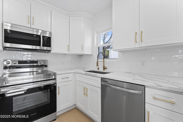 kitchen featuring a sink, white cabinets, light stone countertops, and stainless steel appliances