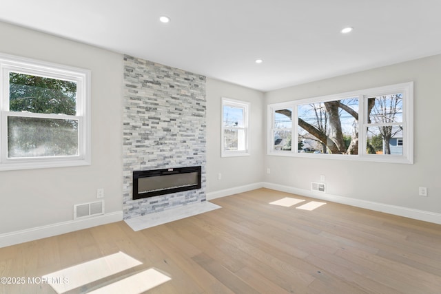 unfurnished living room with recessed lighting, visible vents, wood finished floors, and a fireplace