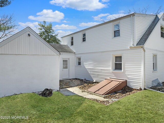 rear view of property featuring a lawn and roof with shingles