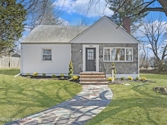 view of front of house featuring stone siding, a front lawn, roof with shingles, and a chimney