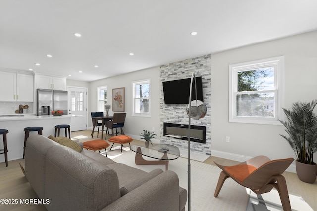 living room with recessed lighting, baseboards, light wood-style floors, and a fireplace