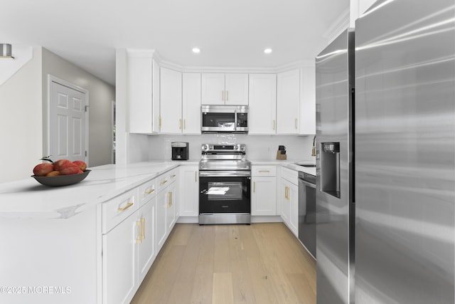 kitchen featuring light wood finished floors, recessed lighting, a peninsula, white cabinets, and stainless steel appliances