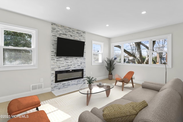 living area with visible vents, wood finished floors, recessed lighting, a large fireplace, and baseboards