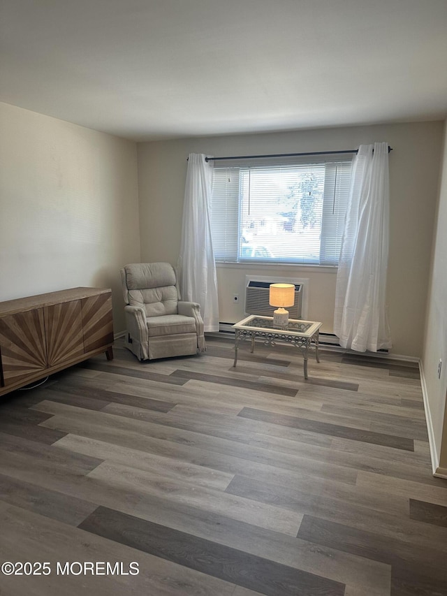 living area with a wall mounted AC, baseboards, and wood finished floors