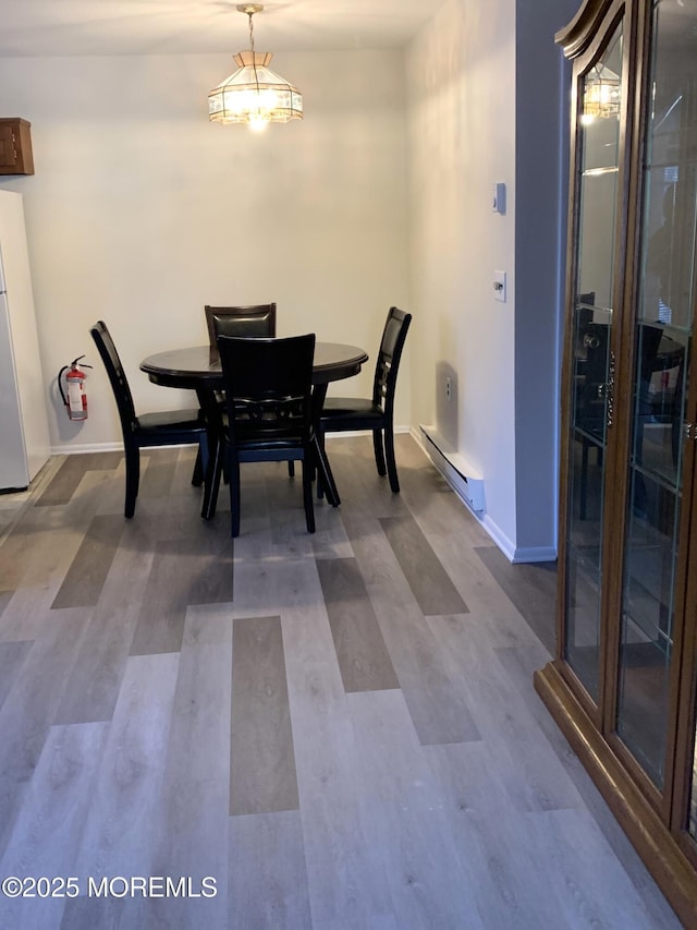 dining space with wood finished floors, baseboards, and a baseboard radiator