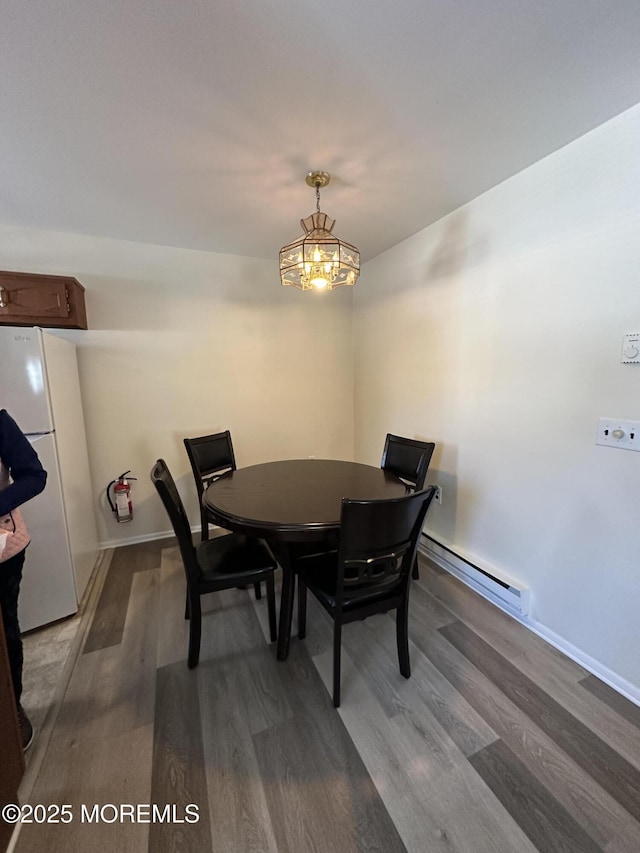 dining area featuring wood finished floors, baseboards, and baseboard heating