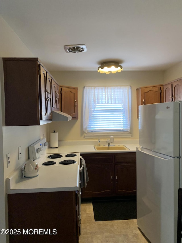 kitchen with visible vents, freestanding refrigerator, a sink, light countertops, and electric stove