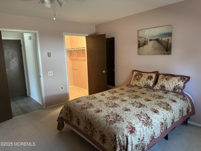 carpeted bedroom with a walk in closet, baseboards, and a closet