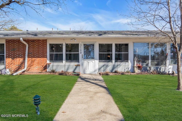 view of front of home featuring brick siding, a front lawn, and a shingled roof