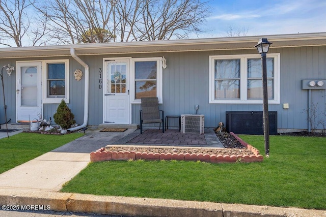 doorway to property with cooling unit and a lawn