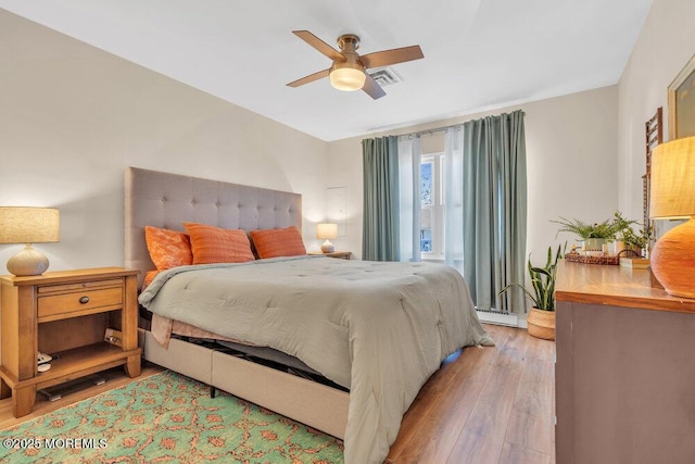 bedroom with ceiling fan, visible vents, and wood finished floors