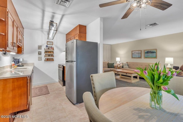 kitchen featuring visible vents, appliances with stainless steel finishes, brown cabinetry, and light countertops