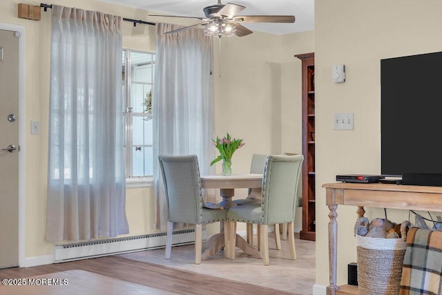 dining area featuring a wealth of natural light, baseboard heating, a ceiling fan, and wood finished floors