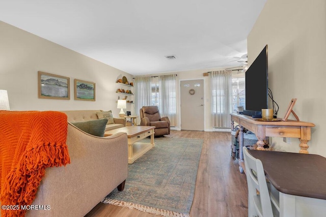 living area featuring visible vents and wood finished floors