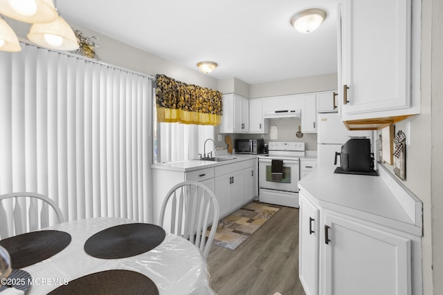 kitchen with under cabinet range hood, white appliances, light countertops, and a sink