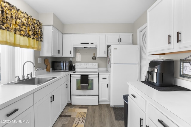 kitchen featuring under cabinet range hood, white appliances, light countertops, and a sink