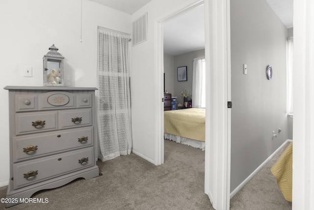 hallway featuring visible vents, baseboards, and carpet