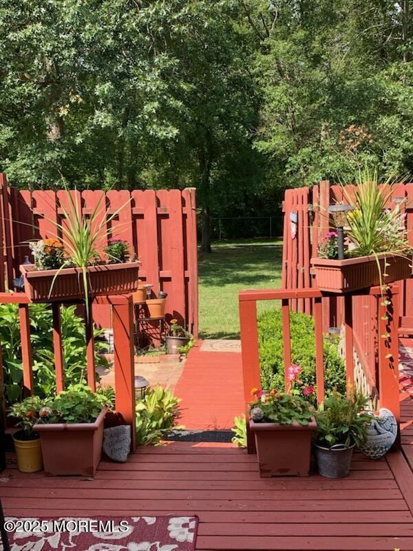 wooden terrace featuring a yard and fence