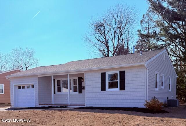 single story home with central air condition unit, a garage, and a shingled roof