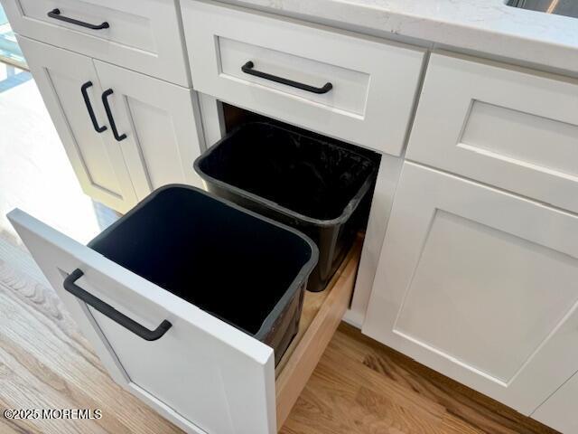 details featuring light wood finished floors, white cabinetry, and light countertops