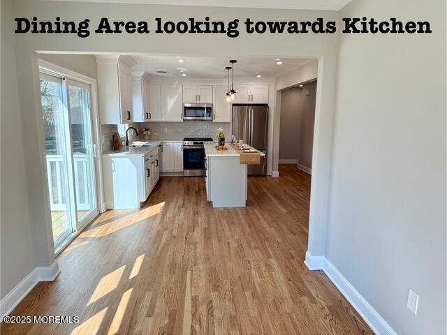 kitchen featuring a sink, appliances with stainless steel finishes, white cabinets, light countertops, and decorative backsplash