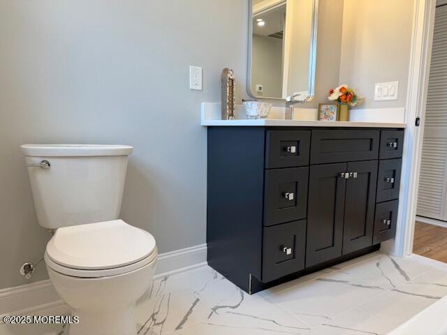 bathroom featuring vanity, toilet, baseboards, and marble finish floor