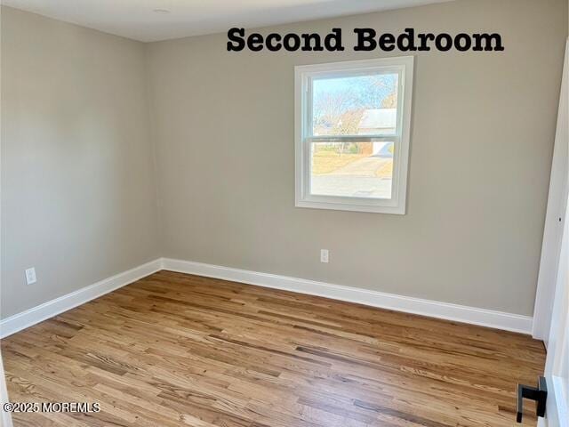 spare room with baseboards and wood finished floors