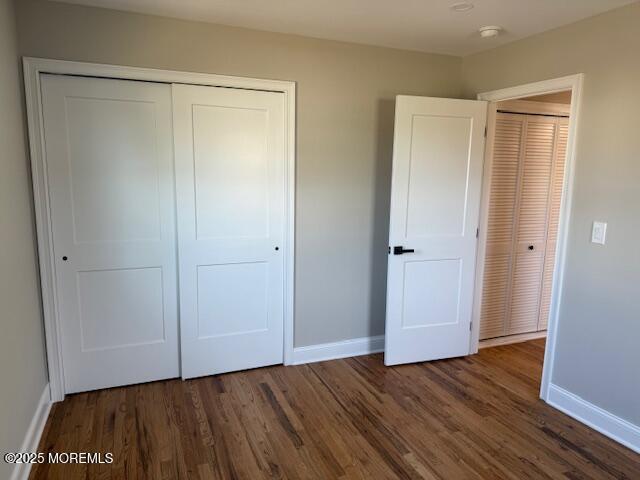 unfurnished bedroom with a closet, baseboards, and wood finished floors