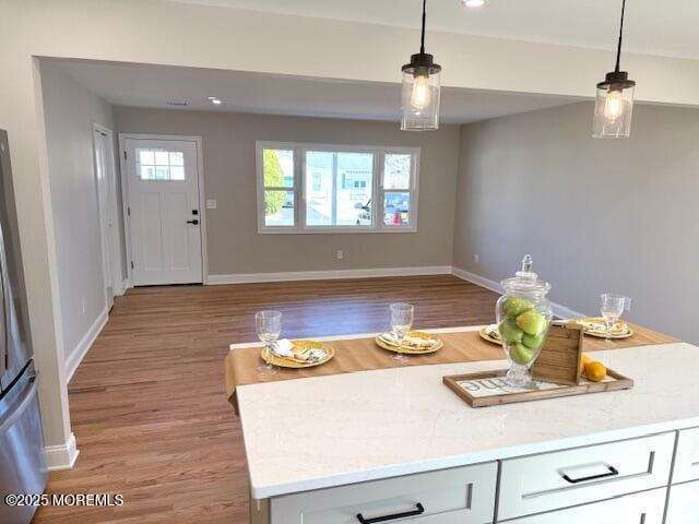 kitchen with baseboards, pendant lighting, a healthy amount of sunlight, and light wood finished floors