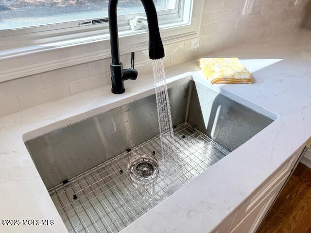 interior details with light stone counters, decorative backsplash, and a sink