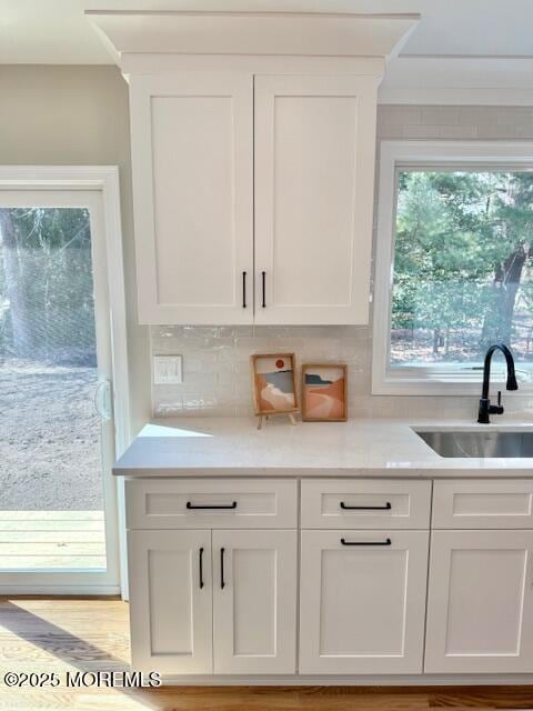 kitchen with white cabinets, light countertops, and a sink