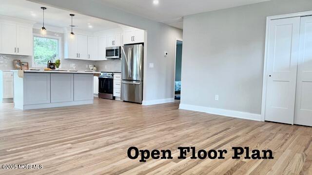 kitchen featuring tasteful backsplash, light wood finished floors, light countertops, appliances with stainless steel finishes, and white cabinets