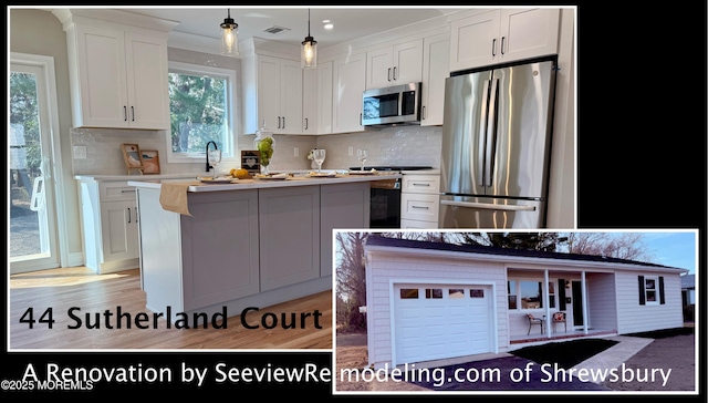 kitchen featuring visible vents, a kitchen island, light countertops, white cabinets, and appliances with stainless steel finishes