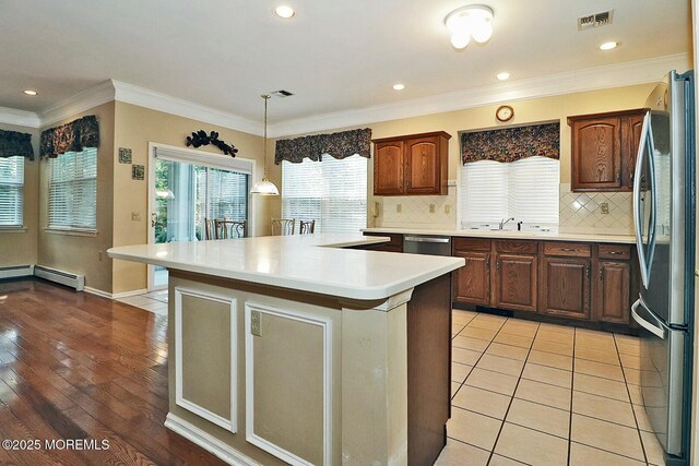 kitchen with visible vents, crown molding, light countertops, stainless steel appliances, and a sink