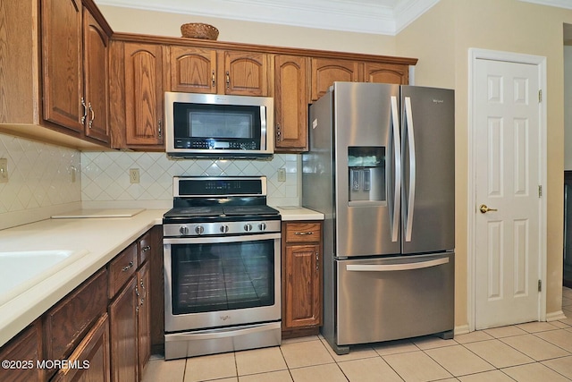 kitchen featuring brown cabinets, ornamental molding, backsplash, stainless steel appliances, and light tile patterned floors