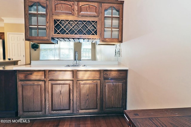 bar with a sink, wet bar, dark wood-type flooring, and crown molding