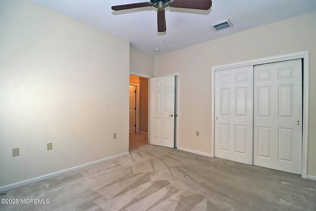 unfurnished bedroom featuring visible vents, a closet, carpet flooring, baseboards, and ceiling fan