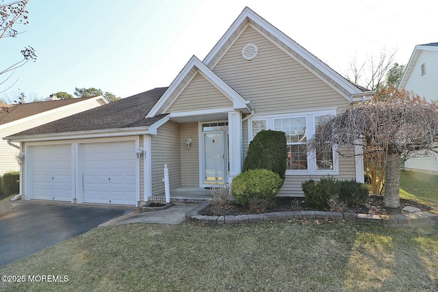 view of front of property with a front yard, a garage, driveway, and roof with shingles