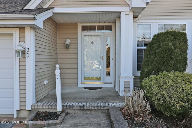 doorway to property with roof with shingles and an attached garage