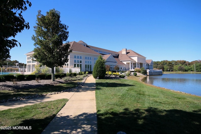 view of front of house with fence, a front lawn, and a water view