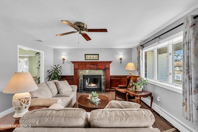 living area with visible vents, wood finished floors, a fireplace, baseboard heating, and ceiling fan