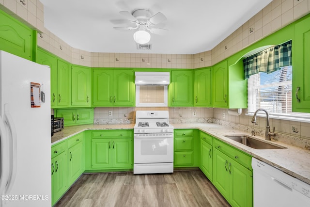 kitchen with white appliances, range hood, visible vents, a sink, and decorative backsplash