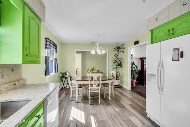 kitchen featuring decorative backsplash, white appliances, an inviting chandelier, and light wood-style flooring