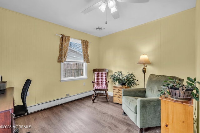 living area with ceiling fan, visible vents, baseboard heating, and wood finished floors