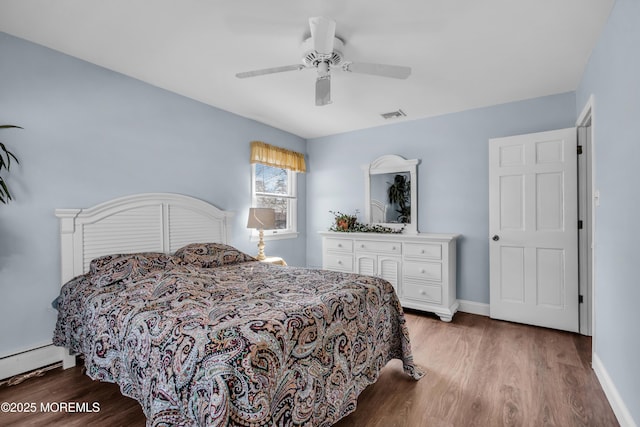 bedroom with visible vents, baseboards, wood finished floors, and a baseboard radiator