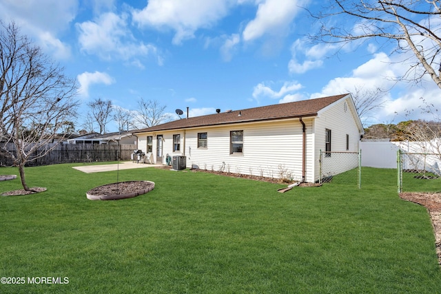 rear view of house with a fenced backyard, central air condition unit, a lawn, and a patio