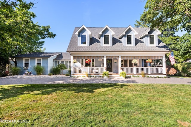 cape cod-style house with covered porch, a shingled roof, and a front lawn