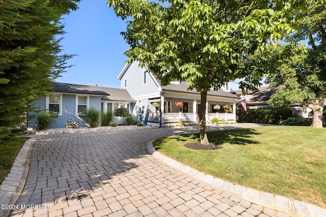 view of front of property featuring a front yard, decorative driveway, and a porch