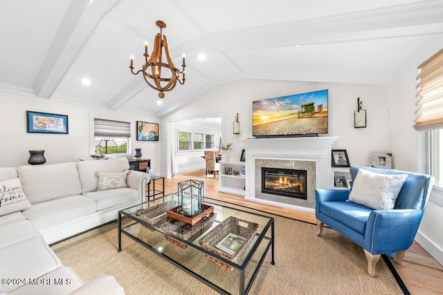 living area featuring lofted ceiling with beams, baseboards, wood finished floors, and a glass covered fireplace