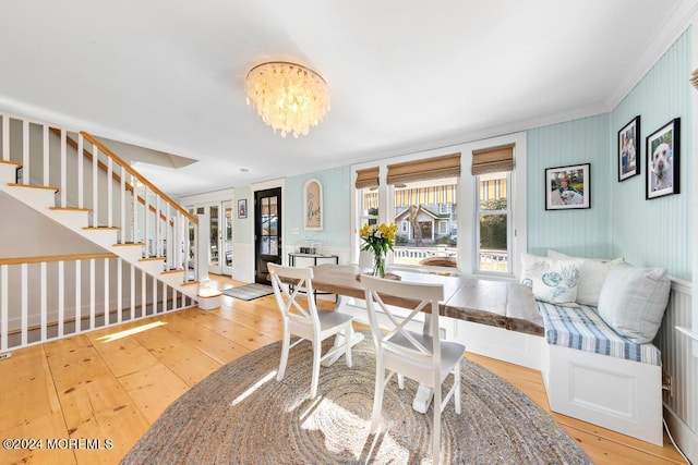 dining room with ornamental molding, stairs, hardwood / wood-style flooring, a notable chandelier, and breakfast area